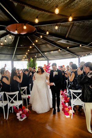 Wedding photography of the groom and bride walking down the isle with guests celebrating around them