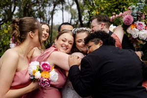 Wedding party members hugging the bride after the wedding ceremony heartfelt wedding photography