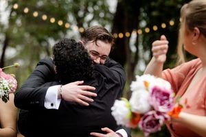 Wedding party members share joyful embraces congratulating the Newley wed couple