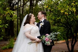 A romantic outdoor wedding scene captured in a lush green garden with a loving couple sharing an intimate moment.