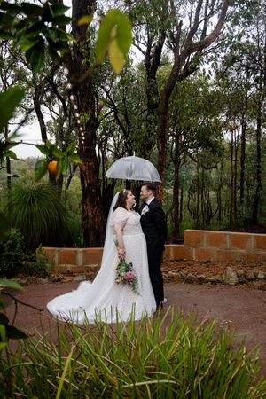 wedding portraits showing newley wed couple in romantic poses standing under an umbrella  on a stone pathway.