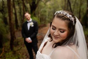 wedding portraits of couple in a wooded landscape, close up of bride looking down groom standing in the background