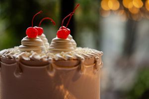 Close-up of wedding cake topped with whipped cream and maraschino cherries