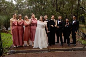 Wedding party members stand together in laughing together