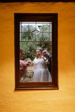bride groom and their bridal party peaking through a vintage window.