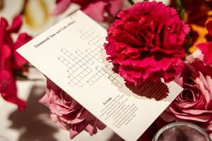 Wedding crossword puzzle activity card decorated with red carnations and pink roses. detail photos of the wedding decor