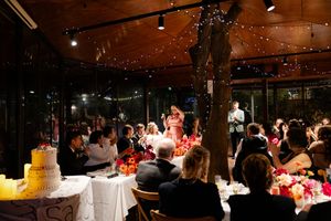 Elegant wedding reception venue with guests seated at tables under warm lighting and floral decorations.