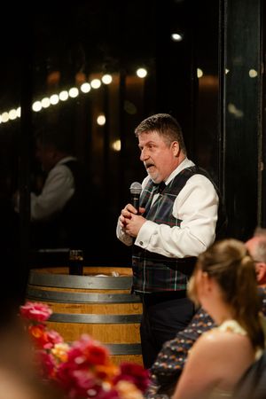 Speaker behind wooden barrel podium giving toast at wedding reception
