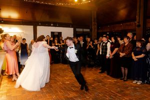 Wide shot of a wedding reception venue with guests watching the bride and groom perform their first dance.