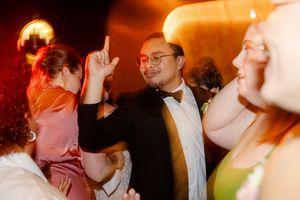 Wedding reception guests dance and celebrate under warm amber lighting during evening festivities.