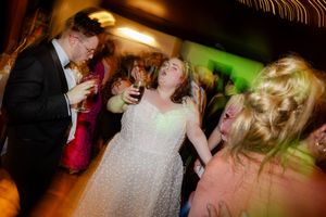 bride and groom dancing enthusiastically at wedding reception.
