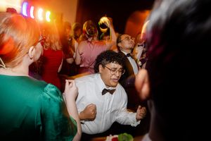 Energetic dance floor moment captured during wedding reception with colorful lighting effects.
