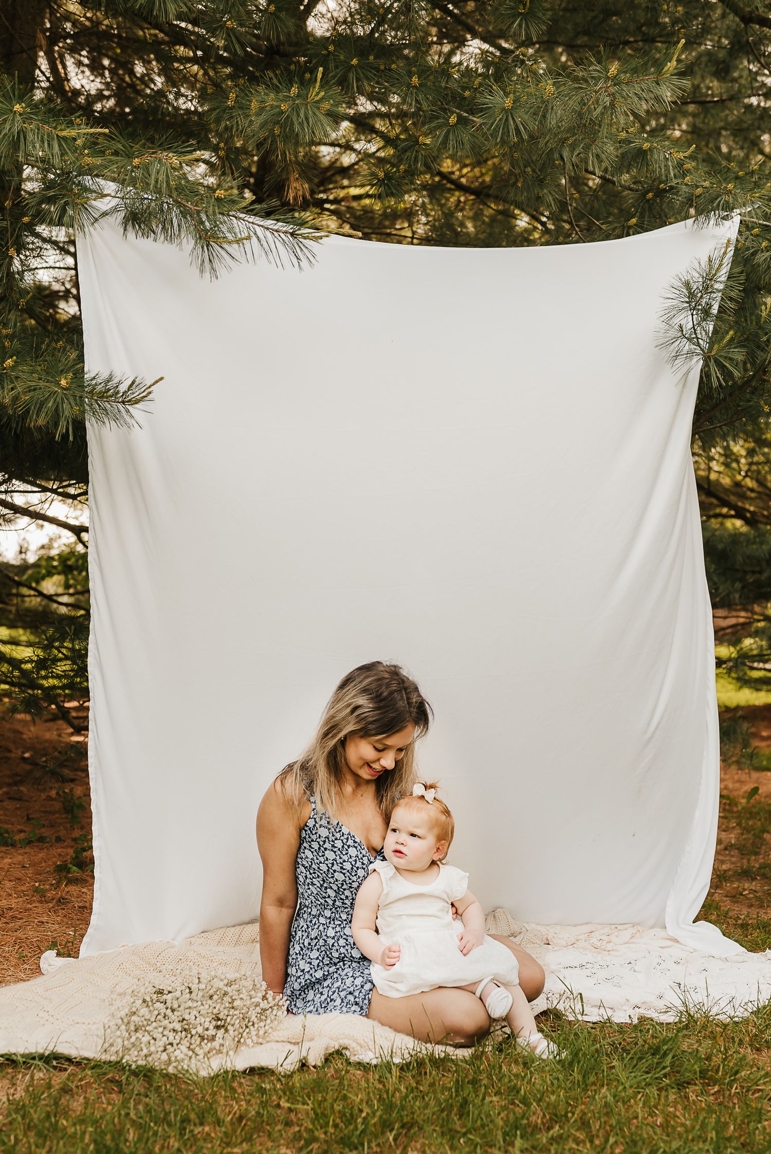Mother and daughter holding hands in a field of spring flowers during a mini session.