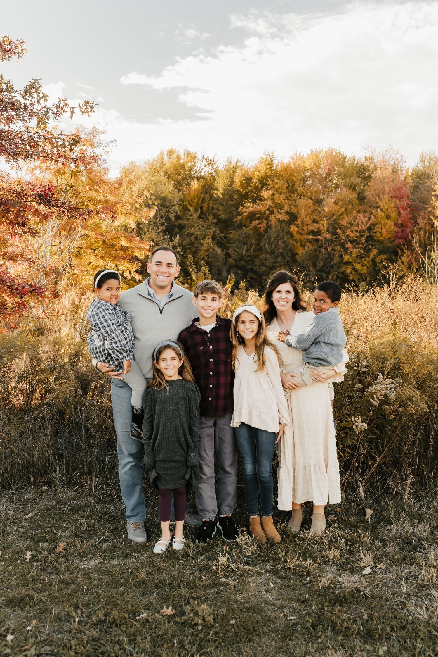 Family of seven laughing together during a fall mini session outdoors.