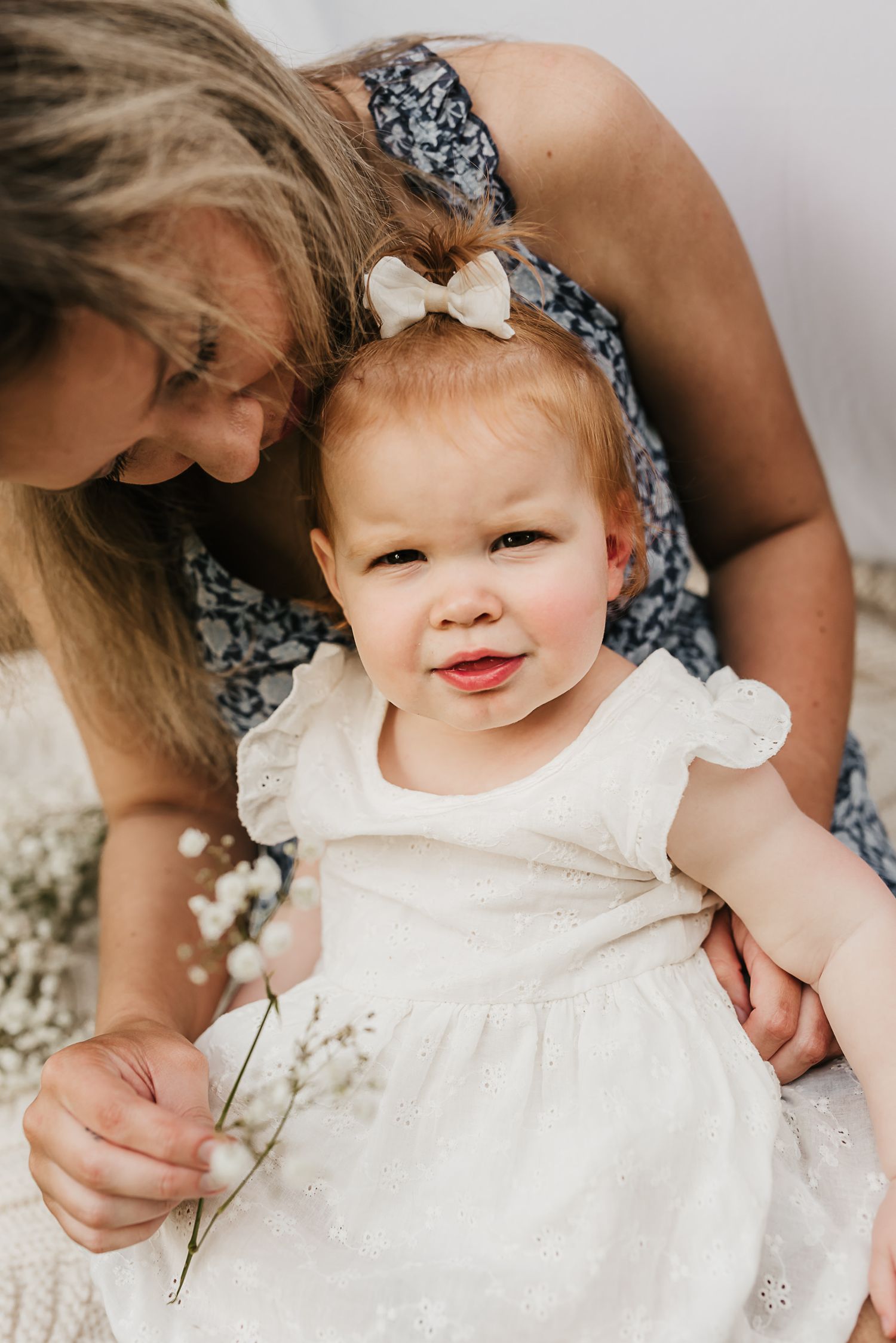 Mother and daughter holding hands in a field of spring flowers during a mini session.