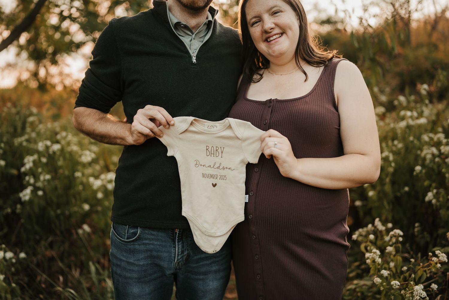Pregnant mother smiling and holding her baby bump during a mini session.
