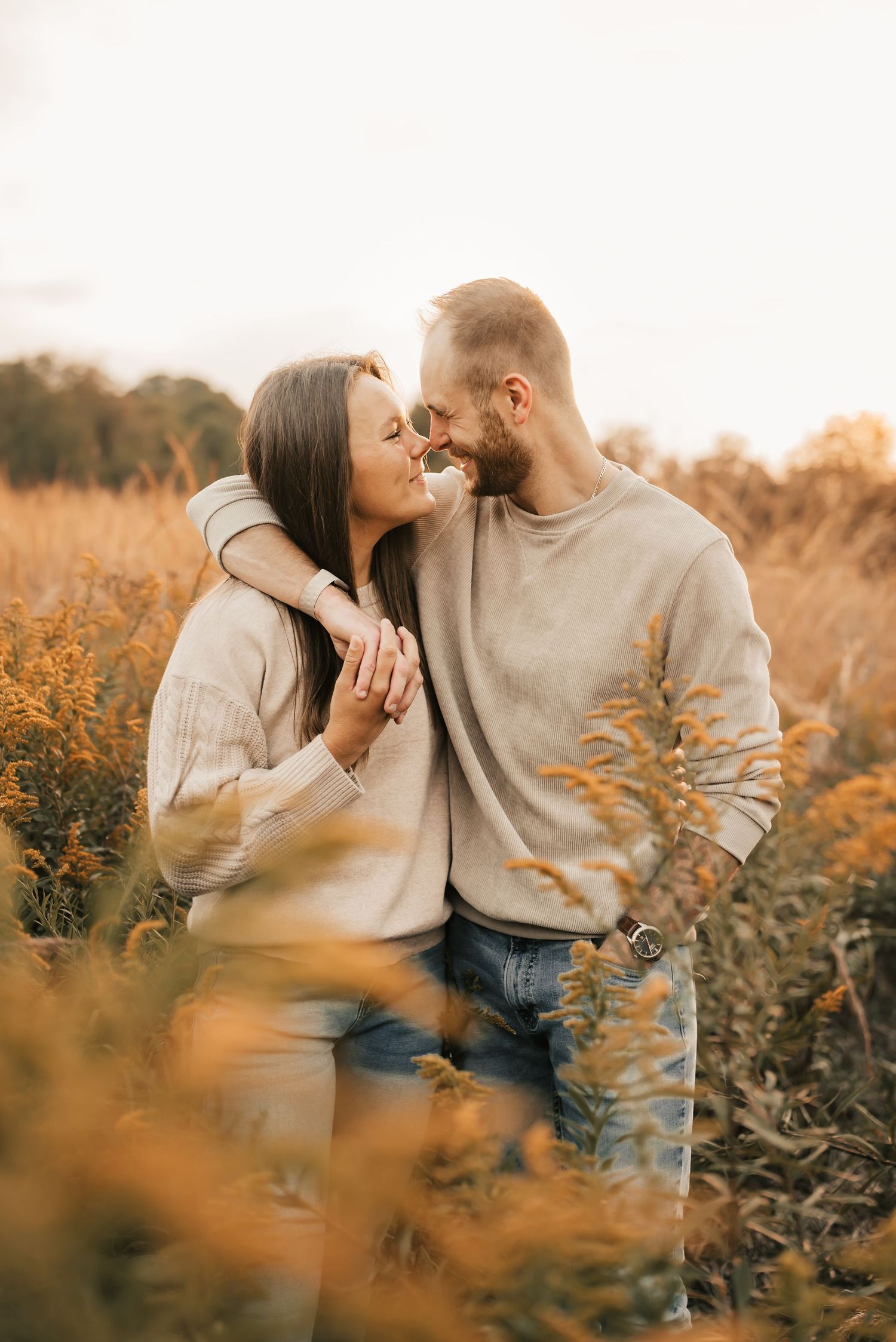 Engaged couple holding hands and laughing during a mini session in the park.