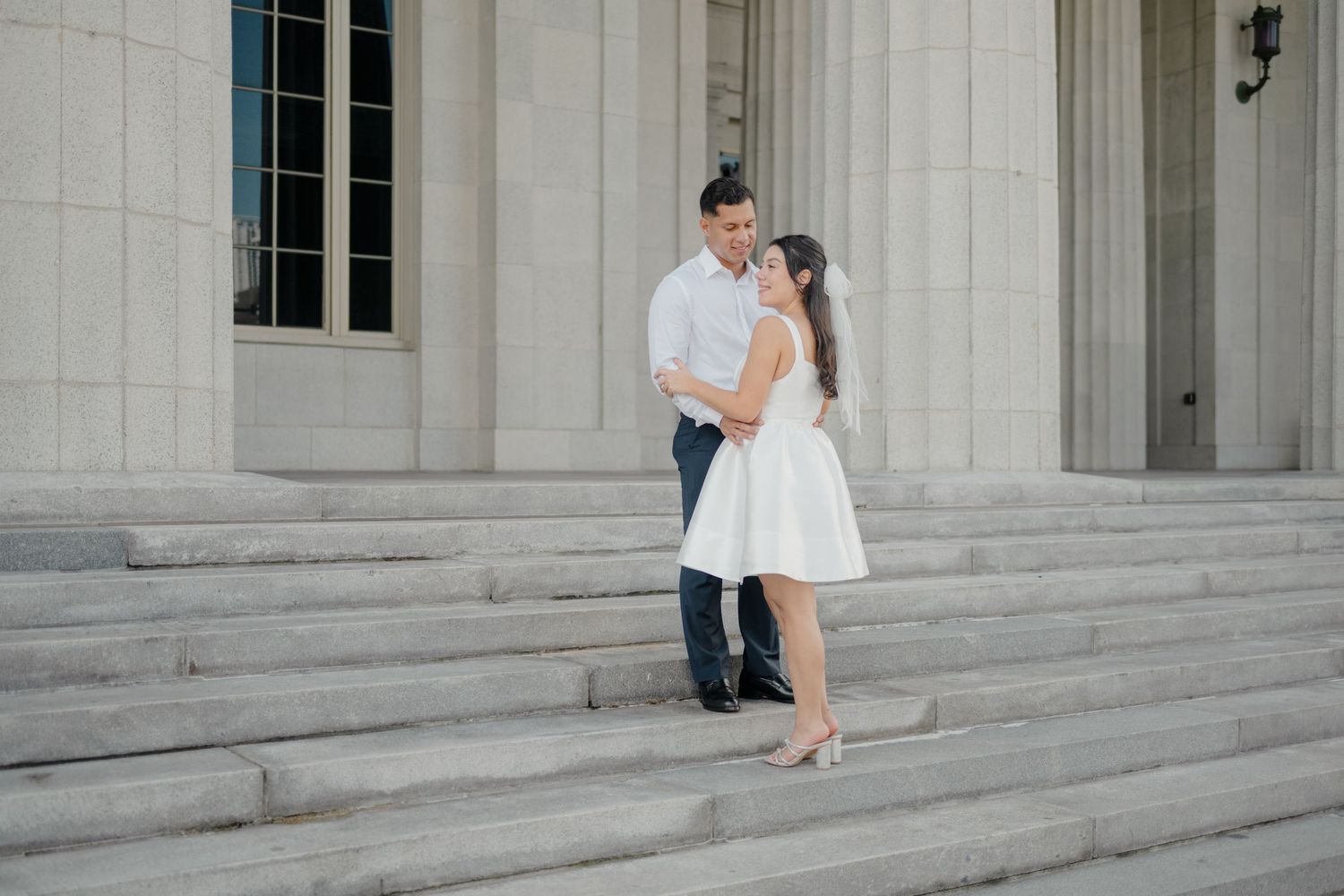 Romantic couple shares a tender moment on grand marble steps of a historic building during their wedding shoot.