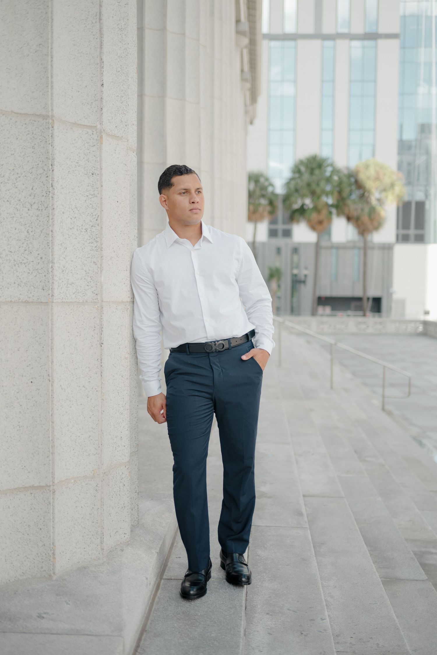 Professional business attire detail showing legs and shoes against modern architectural columns and stone floor.
