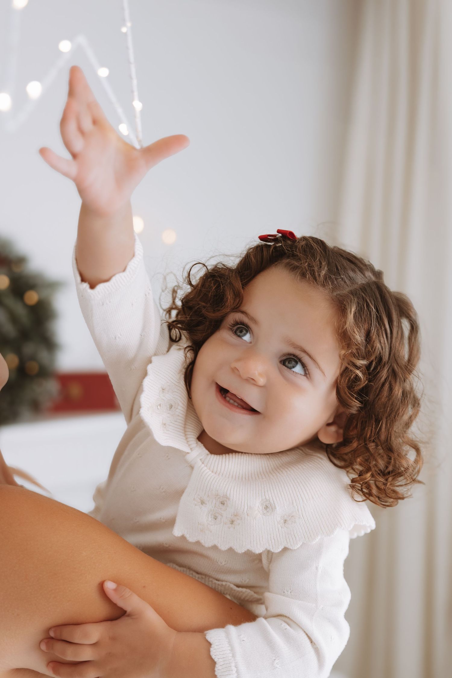 A family poses together in coordinated brown outfits for a cozy holiday photoshoot near a decorated Christmas tree.