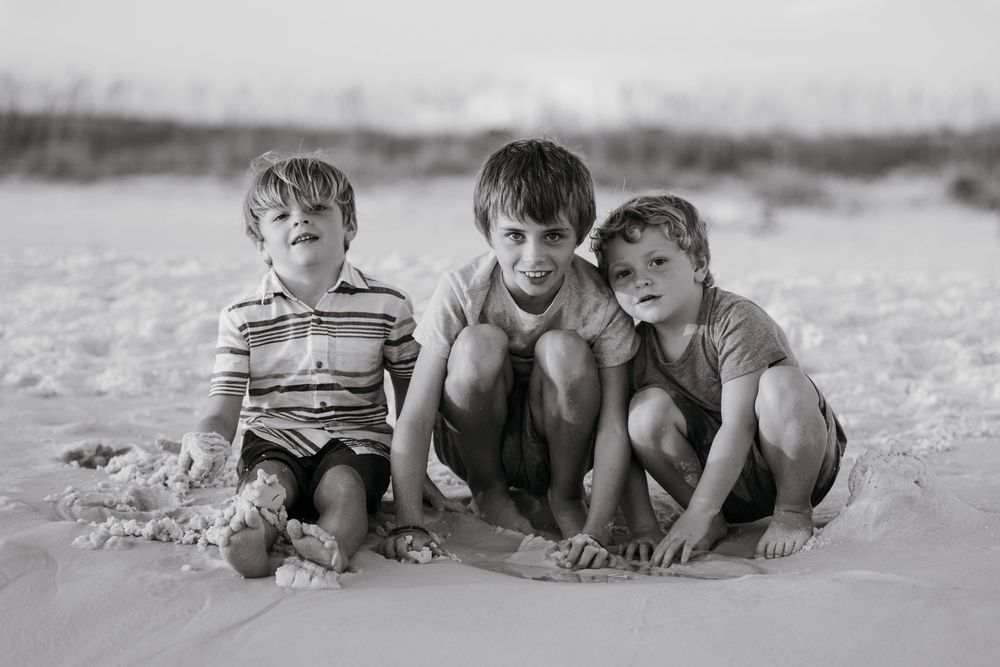 Children playing and crawling together on a sandy beach in black and white vintage style photography.