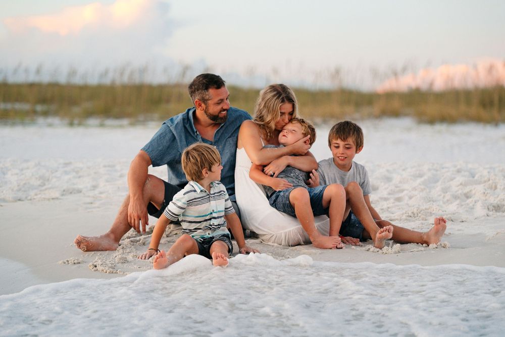 People relaxing together on a white sandy beach at sunset.
