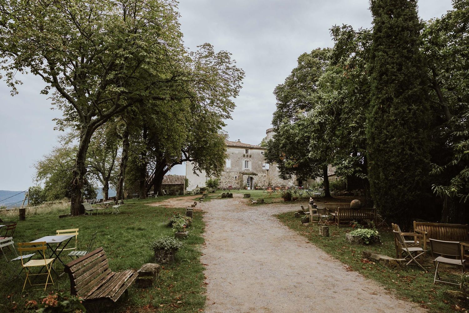 A scenic pathway through a park with benches and trees overlooking a distant mountain landscape.