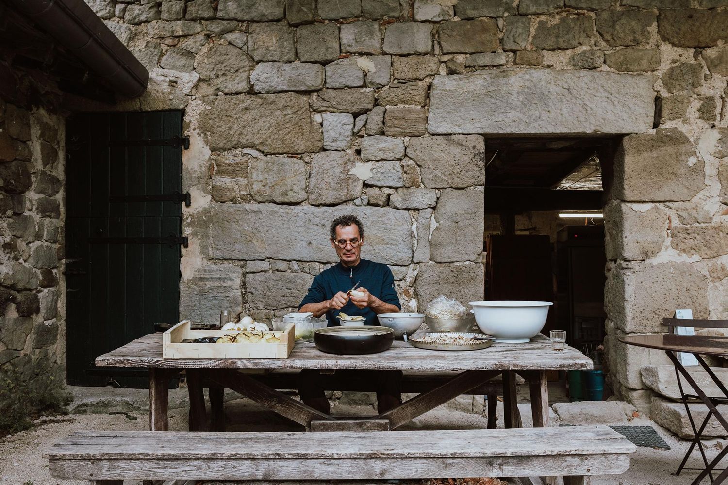 A person works at a rustic stone wall counter in a series of progressive shots showing pottery making process.