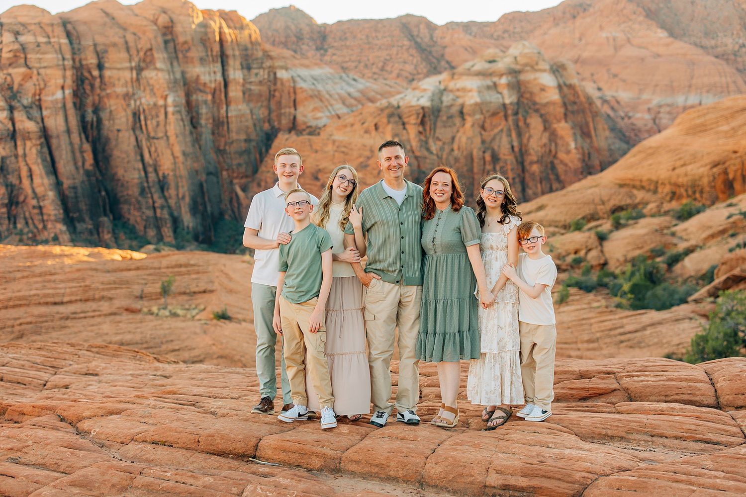 Family portrait session at sunset against stunning red rock formations in the desert landscape.