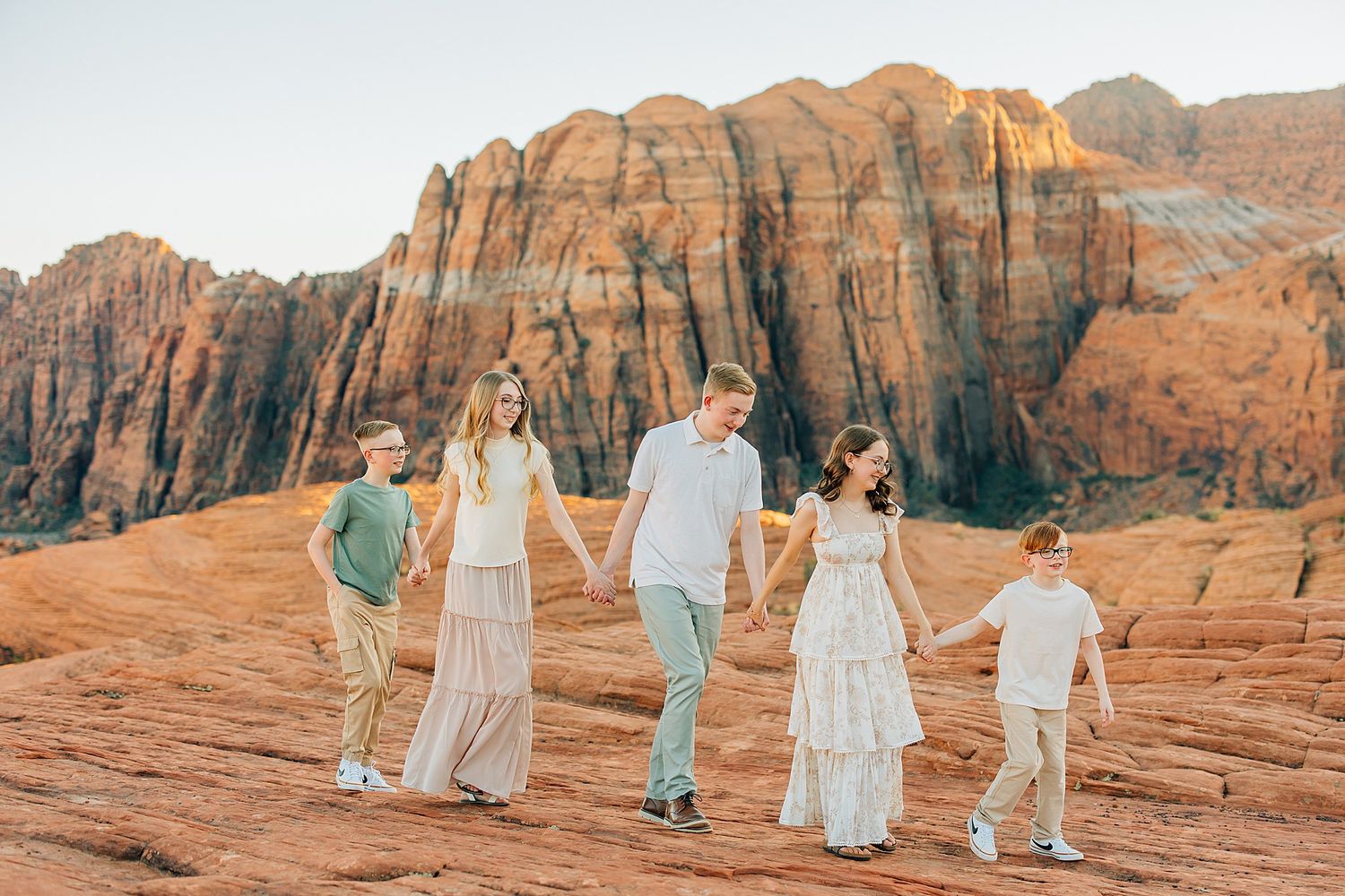Family walking together on red rock formations during a desert photo session.