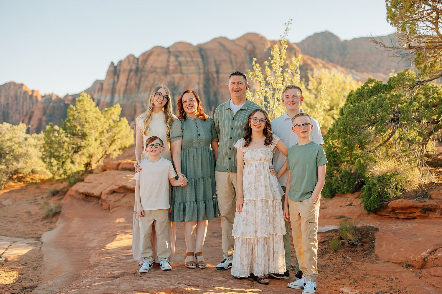 Desert family photography session with golden sunlight illuminating the red rocks.
