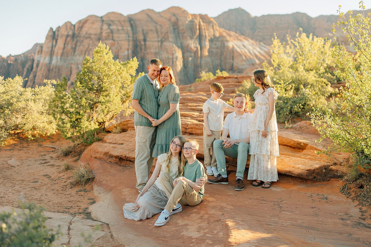 Family portrait session on red rocks with desert mountains in background during golden hour.