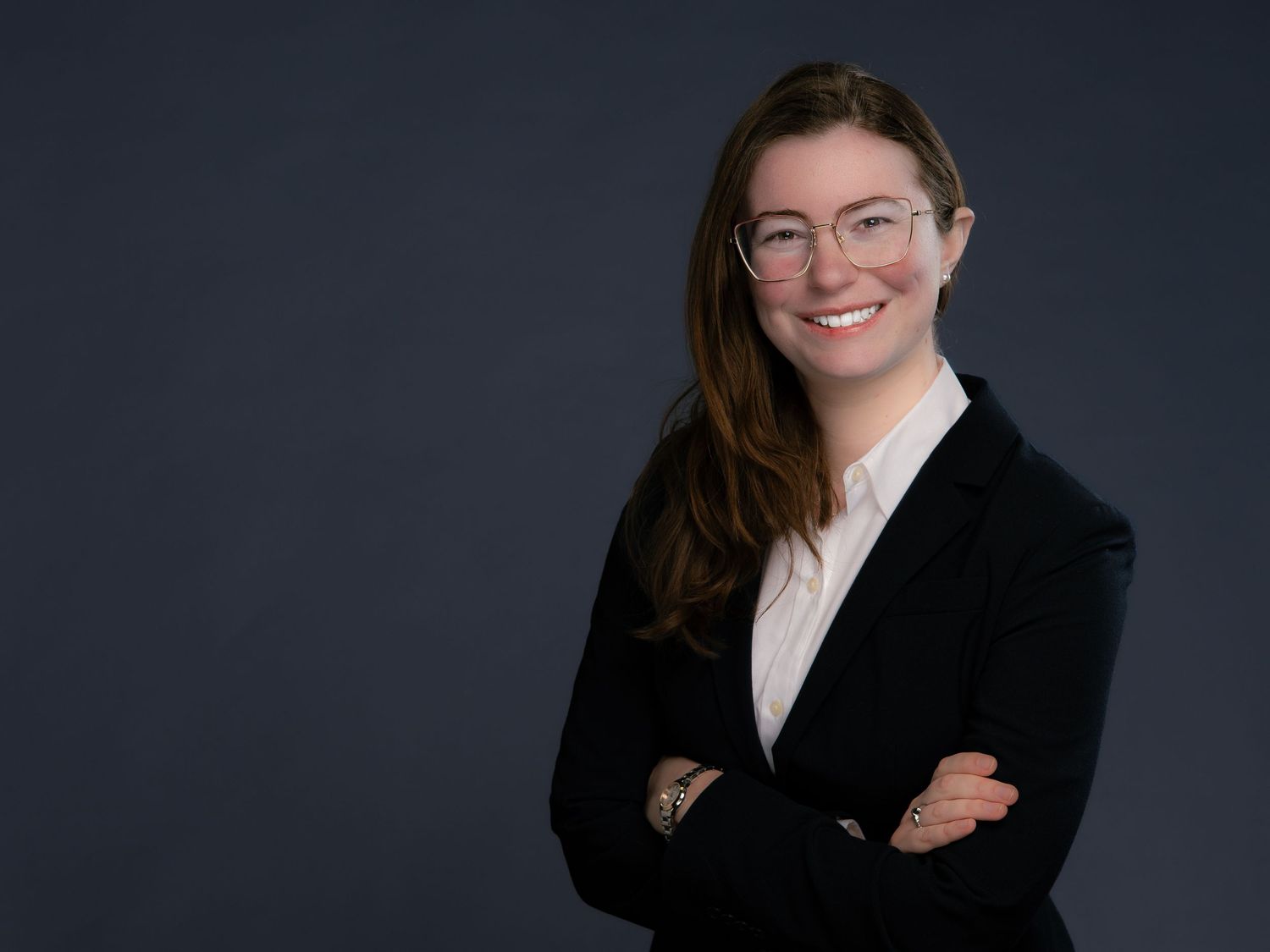 Professional headshot of a smiling man wearing a white dress shirt and blue tie against a light background.