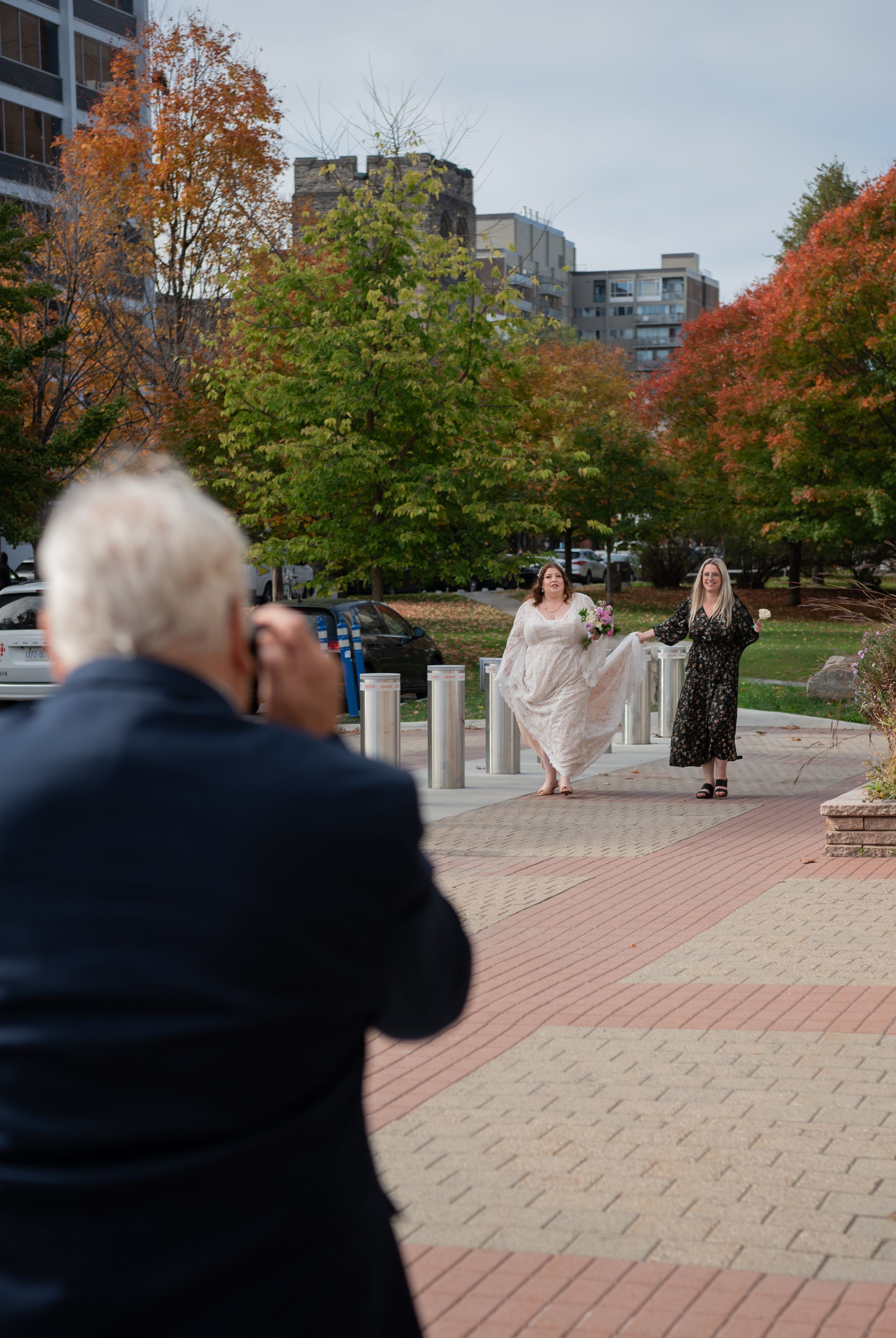 A sequence of motion shots showing a person in a dark jacket photographing someone in flowing fabric on a brick plaza.