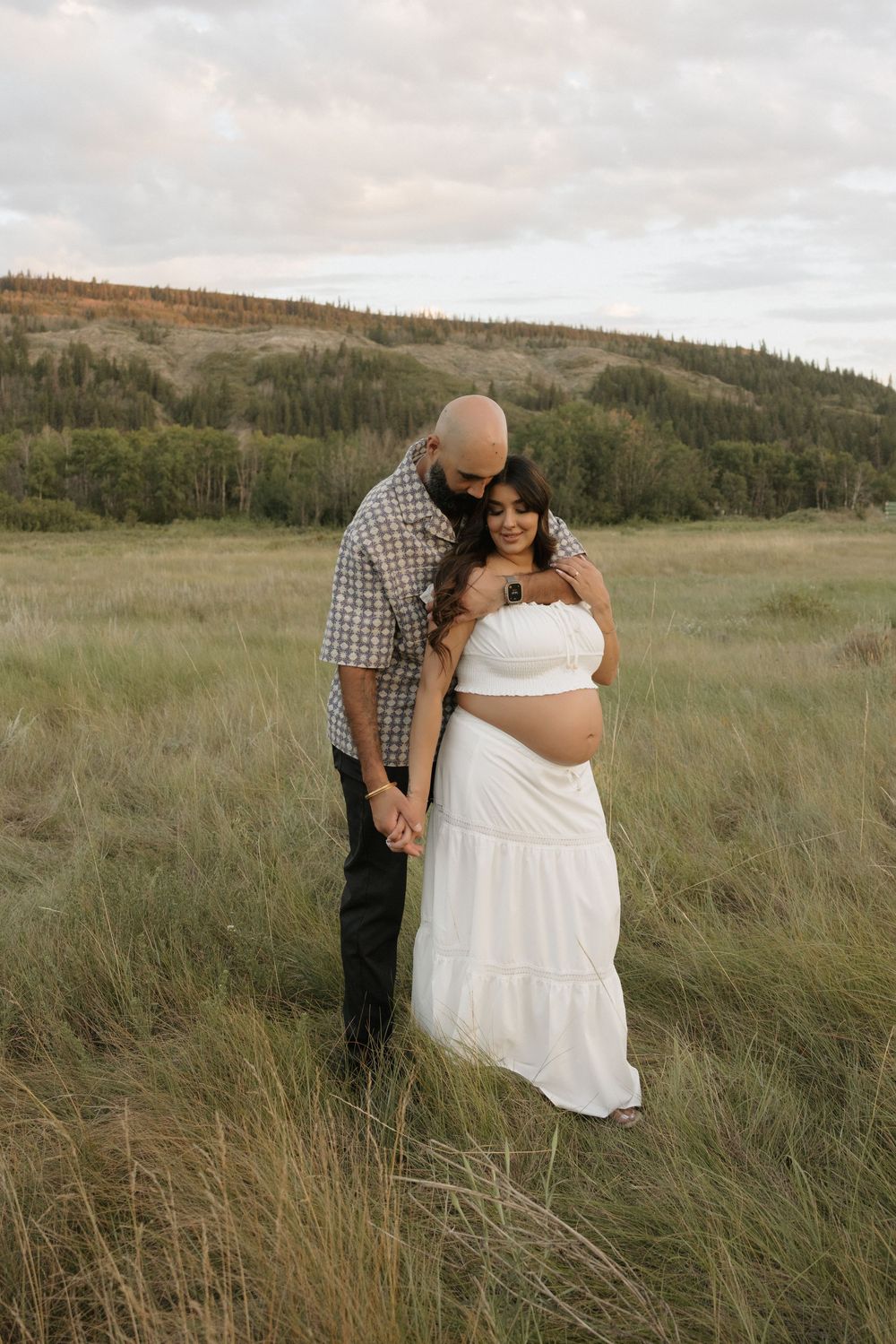 A couple poses in a scenic alberta backdrop during a maternity photoshoot in central alberta