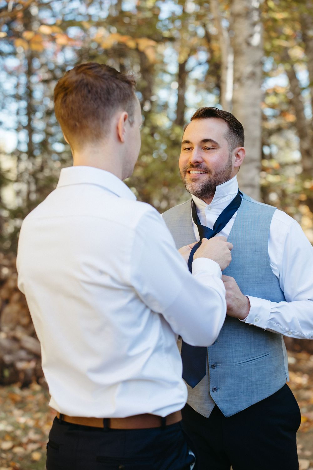 Groom helps husband with tie during outdoor fall wedding, same sex wedding photography in New Brunswick, Moncton wedding photographer