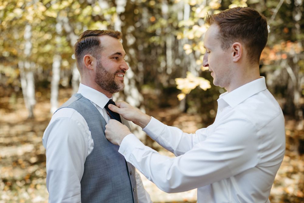 Groom does up tie, getting ready photos outside in Moncton New Brunswick, elopement photographer in Atlantic Canada, outdoor fall wedding