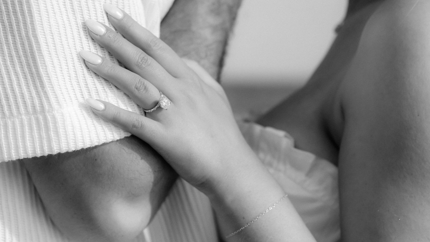 Two hands gently touching and intertwining fingers against a soft neutral background.