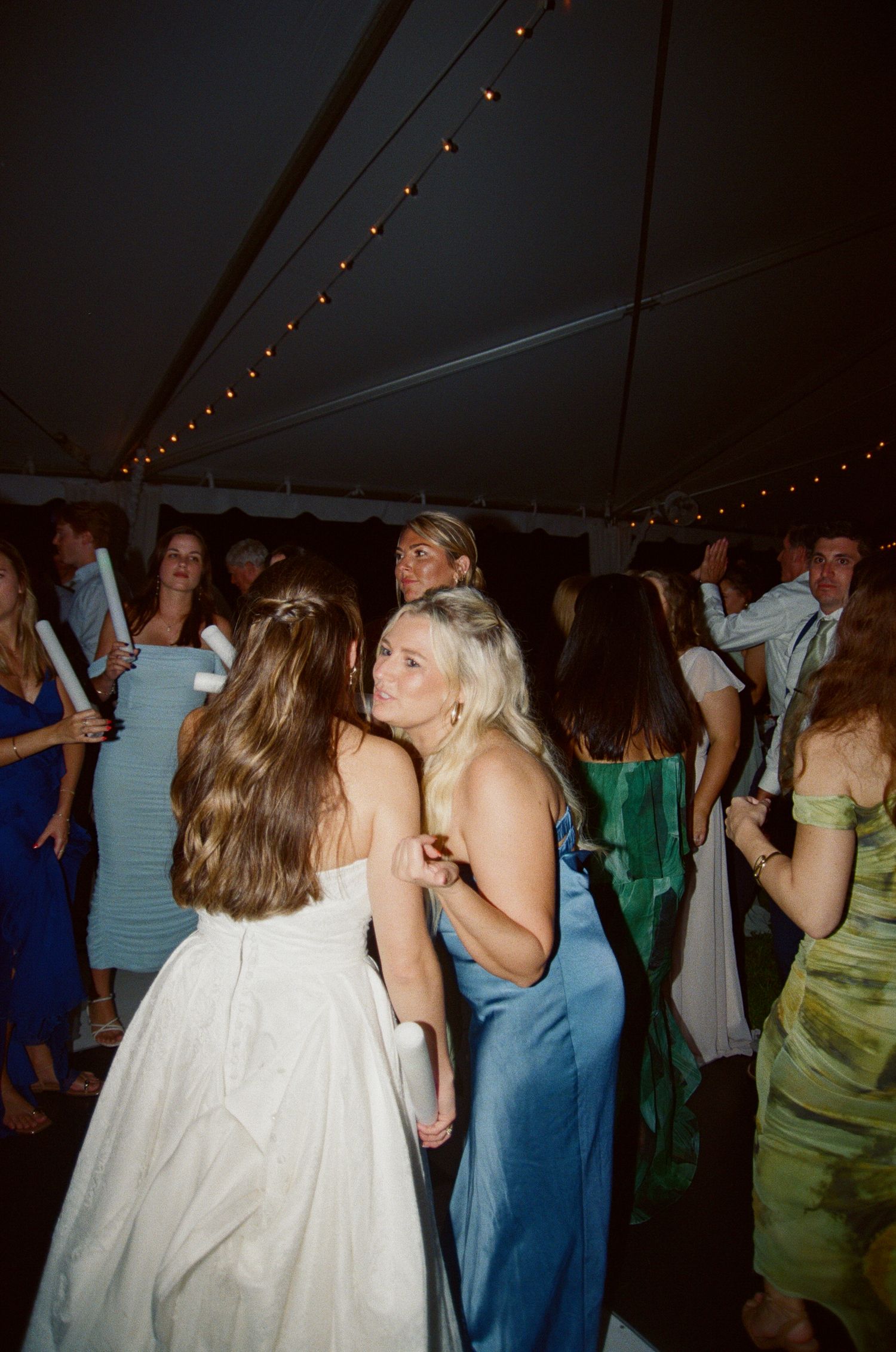 People dancing and socializing at a dimly lit party under string lights.