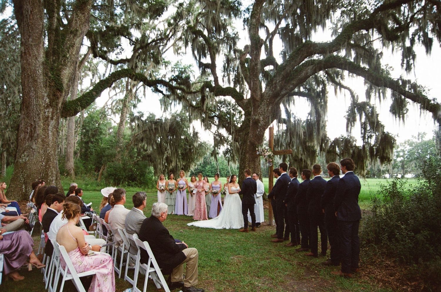 Wedding guests gather under majestic oak trees draped in Spanish moss during an outdoor ceremony in Florida.