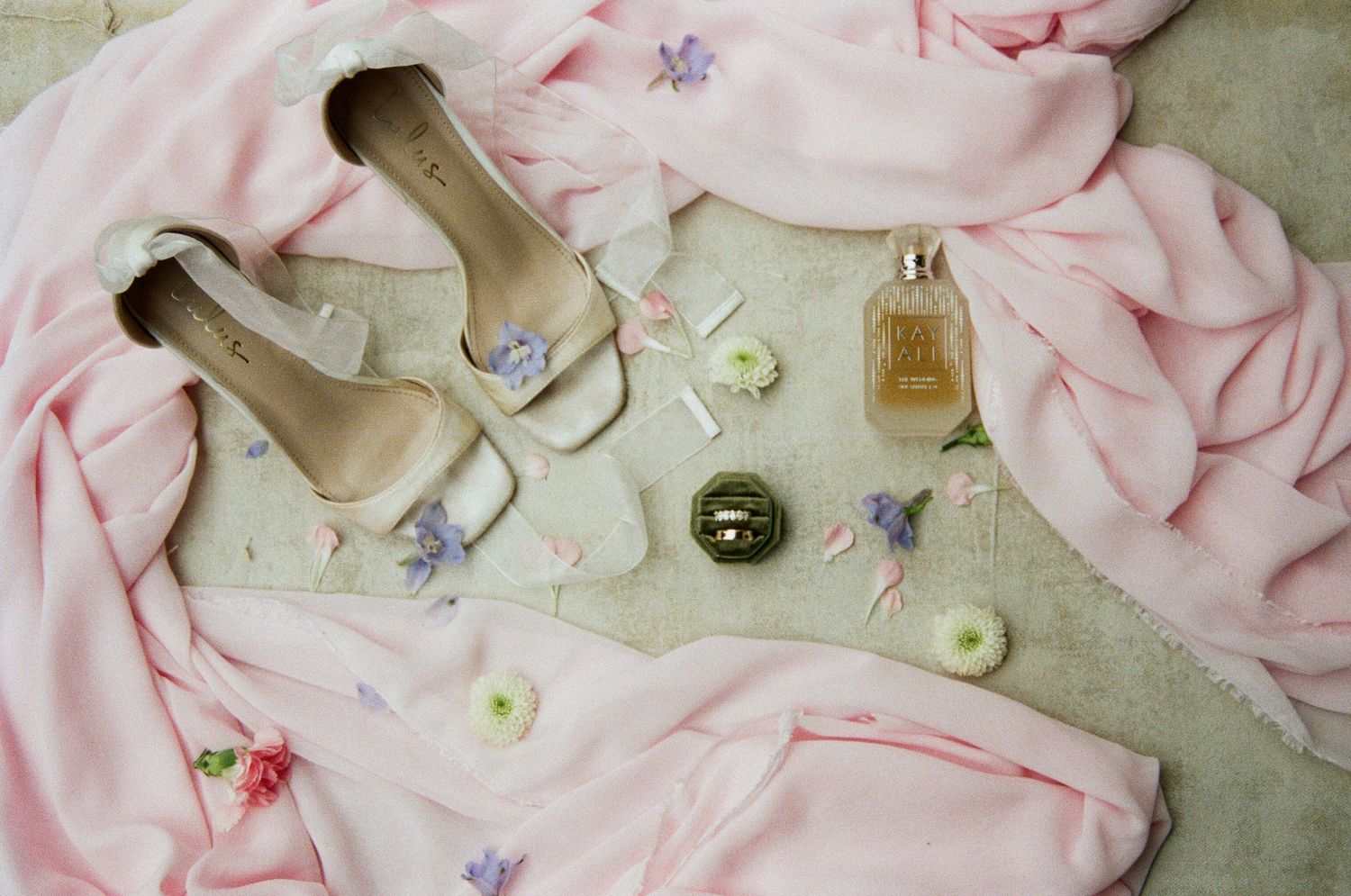 Delicate pink fabric with small floral patterns arranged in a soft, feminine layout with scattered accessories.