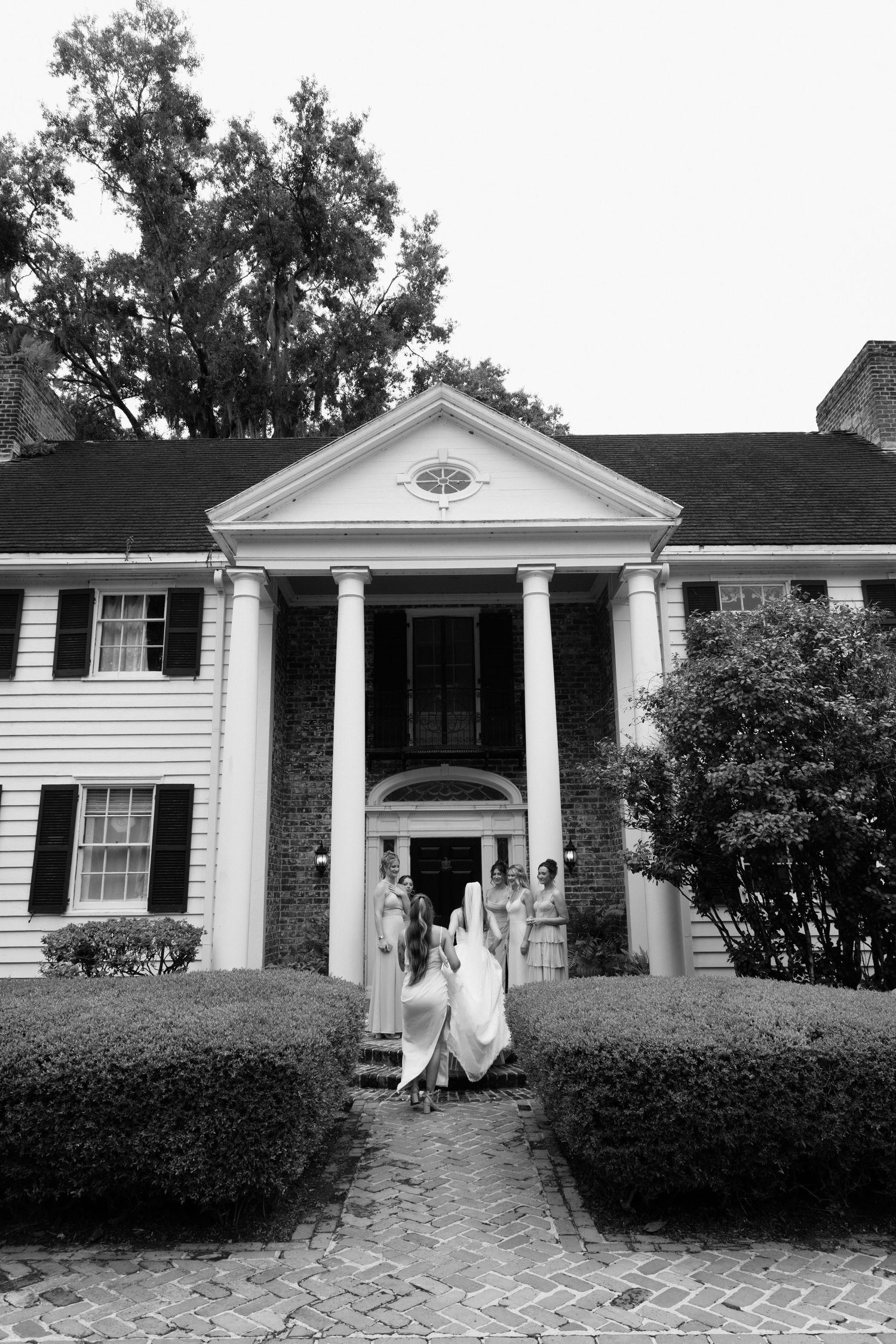 Black and white photo series showing a classic white colonial-style house with columns and shutters from different angles.