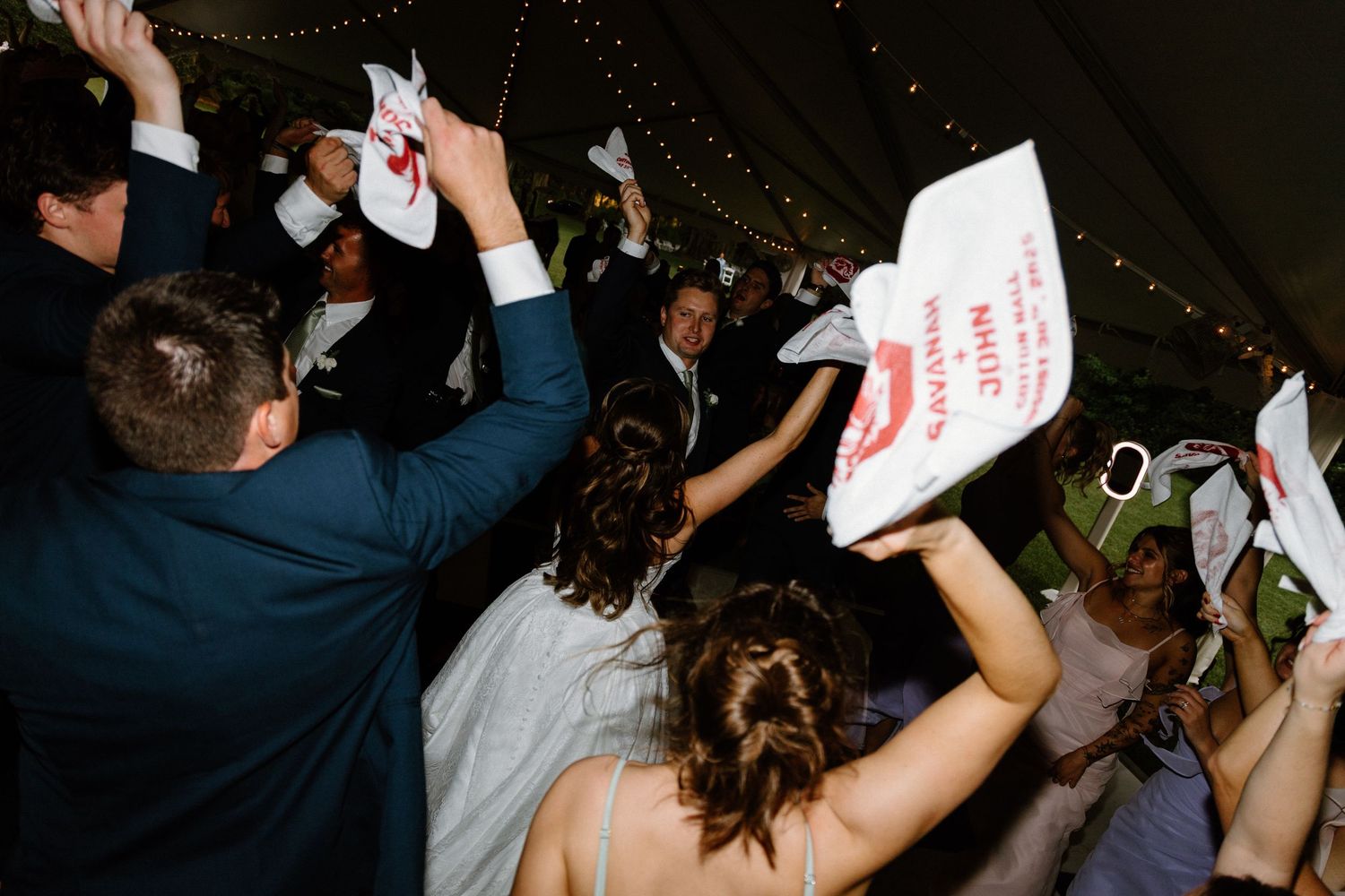 Crowd of concert attendees dancing and holding up signs in a dimly lit venue during a performance.