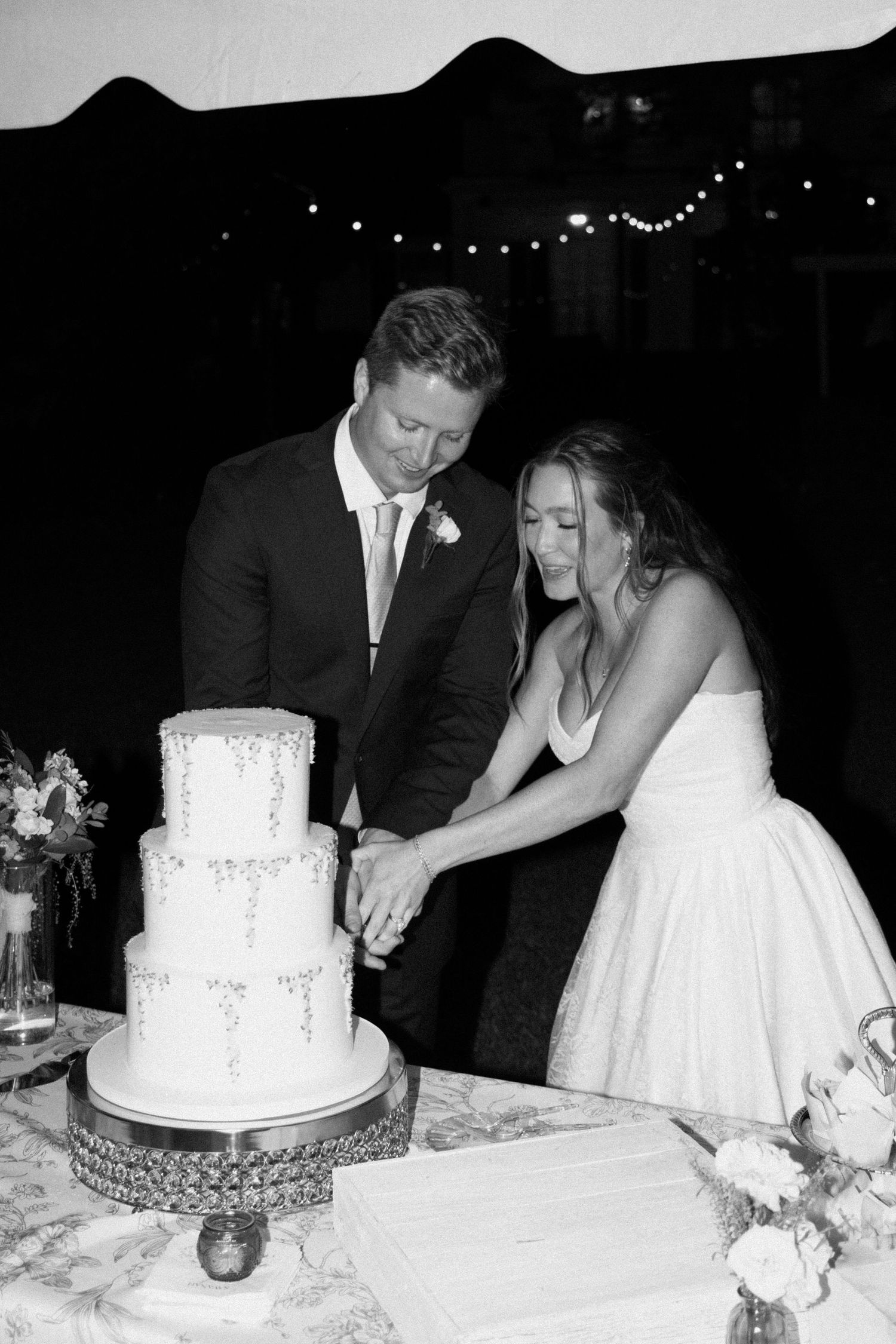 Black and white sequence of a bride and groom cutting their elegant white wedding cake during their reception.