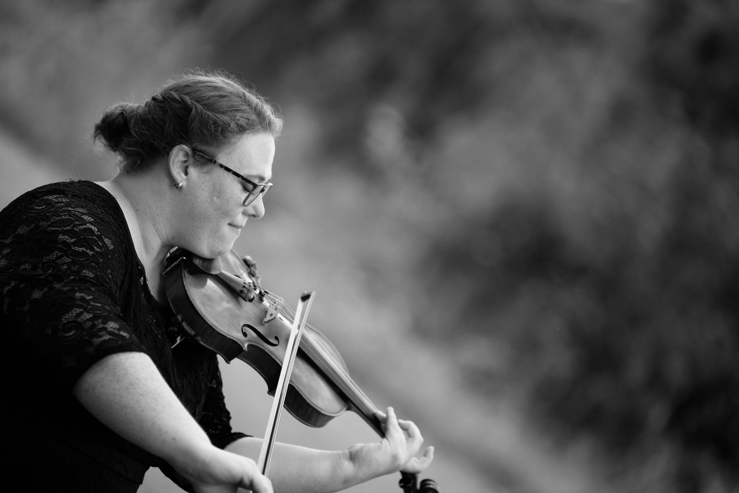 Black and white photo of a violinist performing with focused concentration and dramatic lighting.
