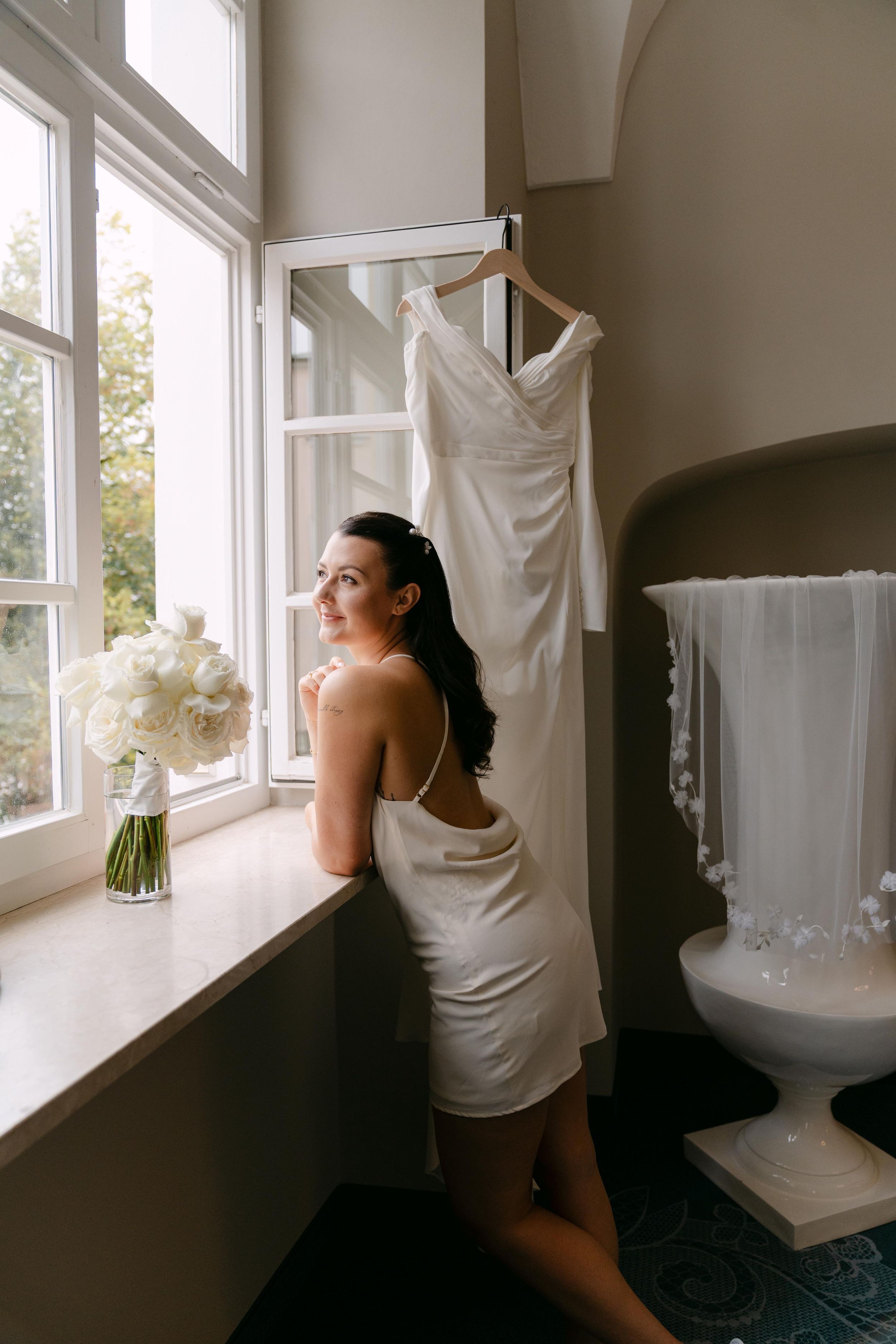 Sequence of a bride in white dress looking out sunny windows during wedding preparations.