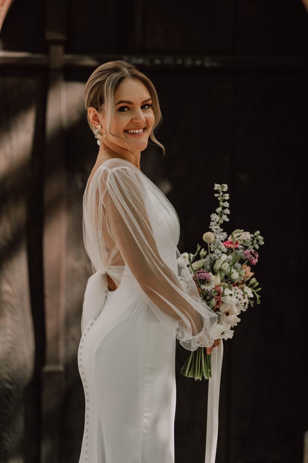 Elegant bridal portraits showing a white dress and delicate bouquet against dark background.