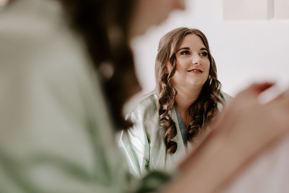 A bride in a white wedding dress poses in soft natural light with blurred background.