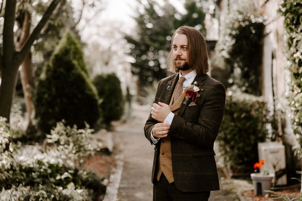 A couple shares a joyful moment together while standing outdoors in a garden setting.