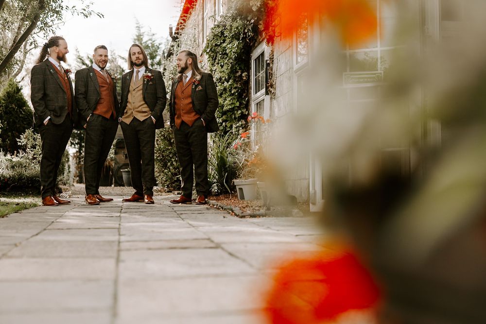 A group of people in formal attire stand together at an outdoor wedding ceremony.